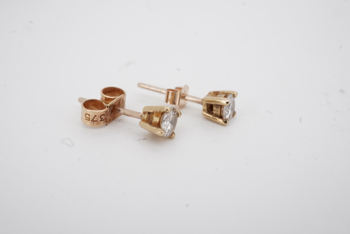 A pair of 9ct gold and solitaire diamond set ear studs, each stone weighing approximately 0.15ct.